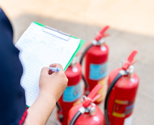 A safety officer is performing the monthly fire extinguisher inspection