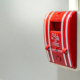 Red fire alarm switch on concrete wall in office building