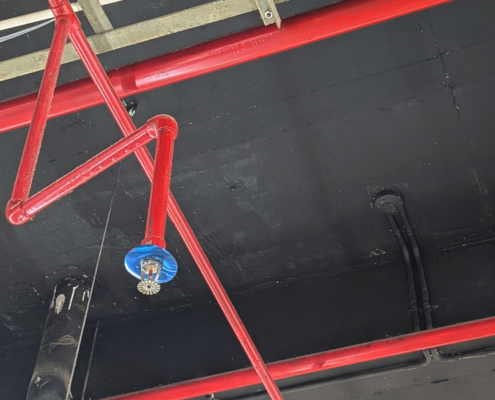 Industrial ceiling infrastructure featuring red fire sprinkler pipes